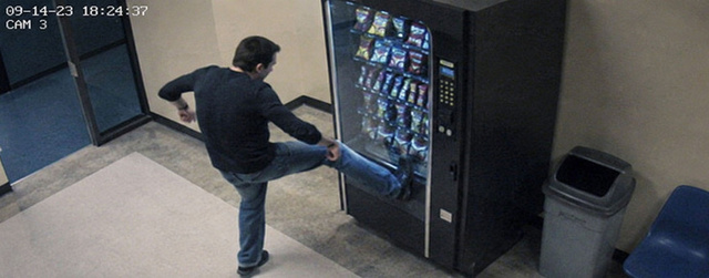 A man kicking a vending machine that took his dollar