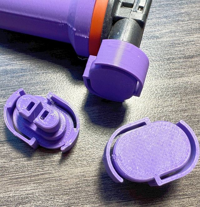 Three purple 3D-printed caps: one clipped over the connector of a bulb in its holder, one showing its two-tower insert, and one showing its smooth back
