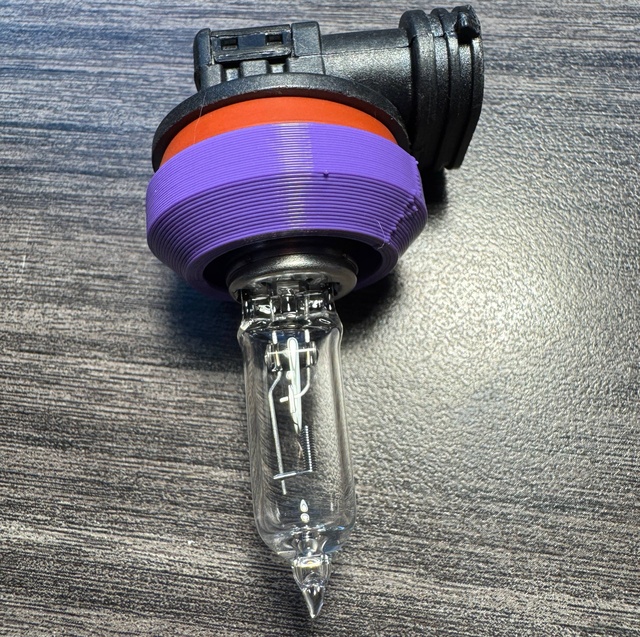 A purple 3D-printed test ring is shown installed on the base of a headlamp bulb.