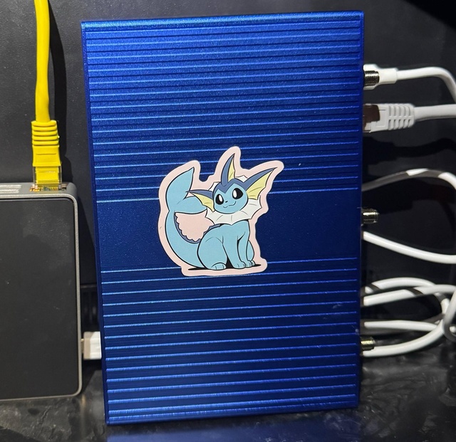 The OpenWrt One standing in the network cabinet, Ethernet in the 2.5G jack.